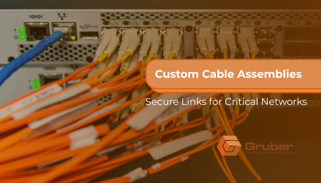 Custom cable assemblies connected to a network switch with orange fiber optic cables – Gruber Communications, Phoenix’s leading cable assembly house, providing secure links for critical networks.