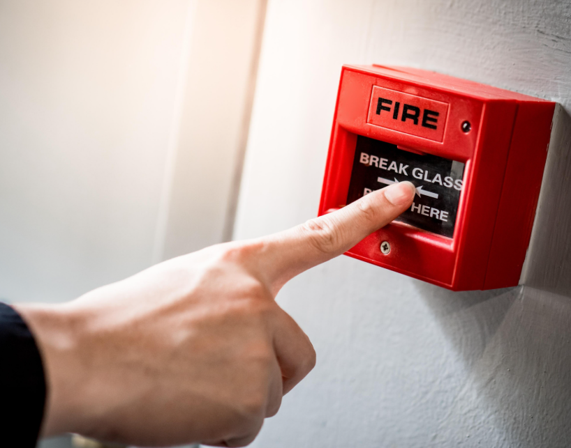 This image features a fire alarm pull station. Fire alarm systems are a critical category of low-voltage applications. The signaling and control circuits for these systems are power-limited and typically operate at 24V DC, which makes them safer to install and maintain than standard electrical wiring.