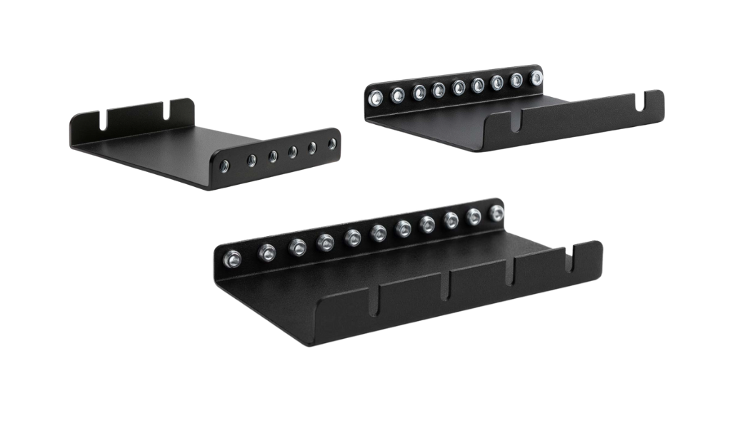 The image features three black fabricated metal mounting brackets or tool holder shelves. These accessories are often referred to as rack extender because they add depth and storage capacity to an existing mounting surface, and they are typically secured using the visible row of bolts or fasteners.